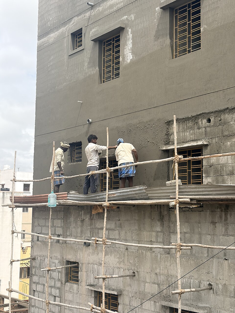 Pedreiros levantando parede de tijolos em obra